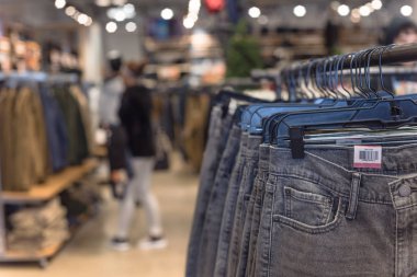 Seçici odak, elbise dükkanı askı ve alışveriş, arka planda tekstil ürünü seçmek bulanık müşteri trendy giyim ile sığ dof görüntü.