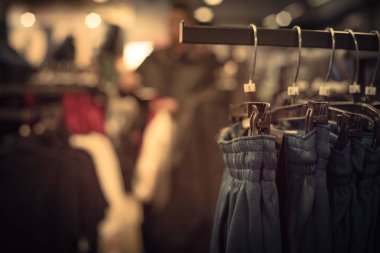 Vintage sesi seçici odak, elbise dükkanı askı ve alışveriş, arka planda tekstil ürünü seçmek bulanık müşteri trendy giyim ile sığ dof görüntü.