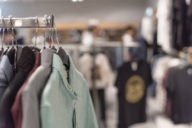 Seçici odak, elbise dükkanı askı ve alışveriş, arka planda tekstil ürünü seçmek bulanık müşteri trendy giyim ile sığ dof görüntü.