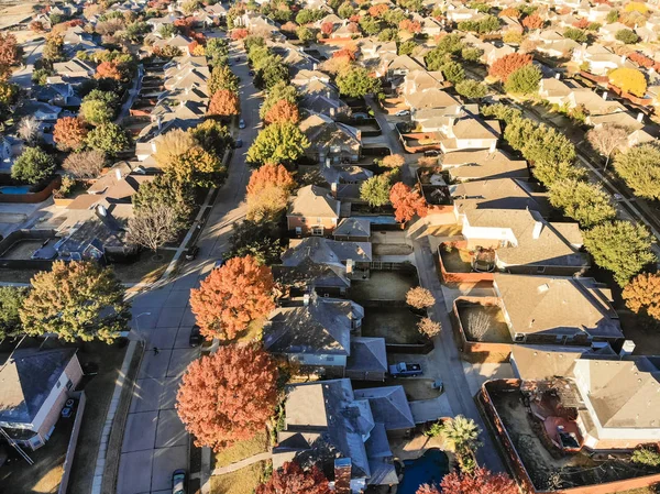 Aerial view planned unit development suburbs of Dallas, Texas, USA in autumn season. Flyover residential area with row of single-family homes and gardens, colorful fall foliage leaves