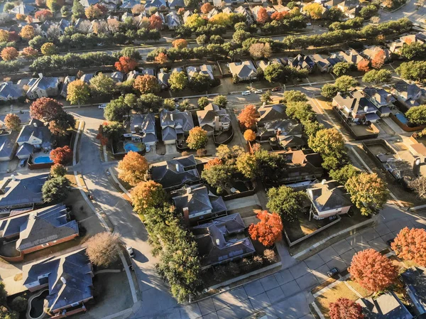 Aerial view planned unit development suburbs of Dallas, Texas, USA in autumn season. Flyover residential area with row of single-family homes and gardens, colorful fall foliage leaves