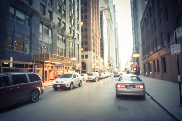 Vintage tone blurred busy street alley in downtown Chicago at sunset. Defocused bokeh light from long line of cars on street