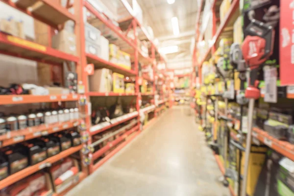 Blurred abstract selection of garden tools on rack shelves at hardware store in America. Defocused background variety of trimmer, blower, chain saws, hedge trimmer for gardening works