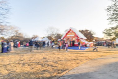 Zıplayan ev ve üst ve Gingerbread Jubilee, Noel Kış Festivali yakın yerleşim bölgesinde varoşlarda Dallas, Texas, ABD Genel park, sıraya queuing çocuklar soyut bulanık
