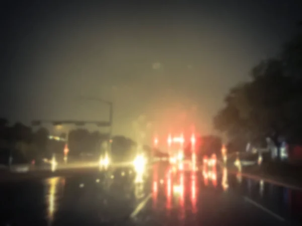 Vintage tone blurred abstract stopped car at traffic light intersection and rear lights reflection on the rainy asphalt road. Defocused cityscape and transportation background in America