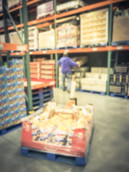 Blurred motion warehouse staff operating manual forklift to stock goods. Defocused big-box store aisle shelves in America