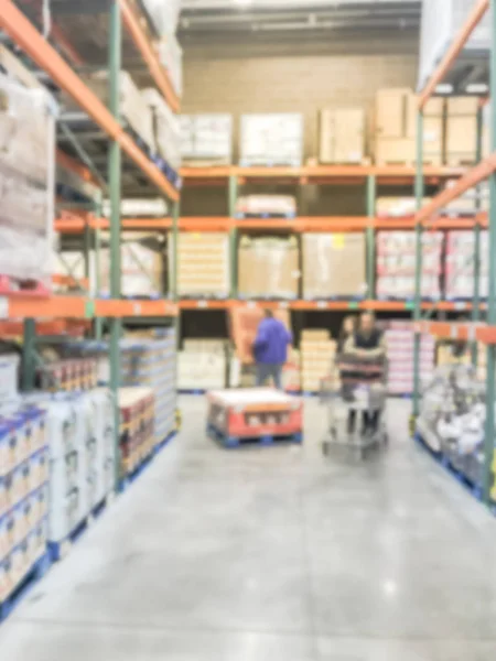 Blurred motion warehouse staff operating manual forklift to stock goods. Defocused big-box store aisle shelves in America