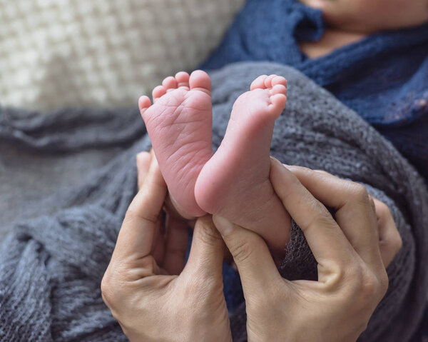 Close-up baby feet in mother hands. Mom and her Asian child. Happy Family concept. Macro image of Maternity