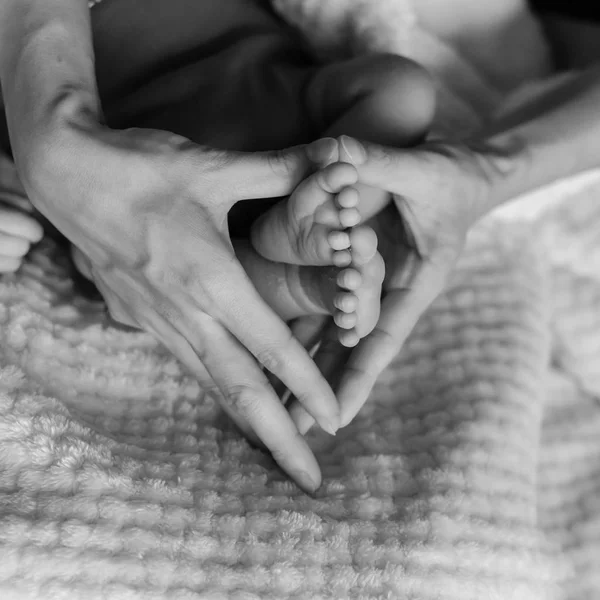 ビンテージ トーン クローズ アップは母親の手で生まれたばかりの赤ちゃんの足を聞く形を保持しています 居心地のよい毛布背景に並ぶぬいぐるみで愛らしい男の子爪先のマクロ写真 — ストック写真