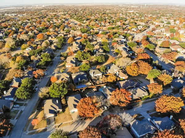 Aerial view residential neighborhood with sprawl subdivision in background. Flyover single-family houses with colorful autumn leaves in Flower Mound, Texas, USA, blue sky