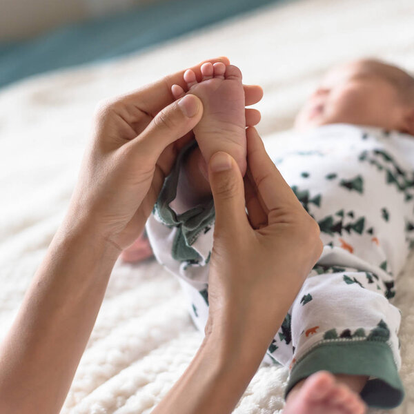 Little toes of newborn Asian baby in his mom hands. Love and protection concept