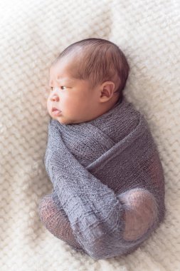 Mor örme tiftik şal giysili Asya bebek çocuk. 6 gün eski bebek yatakta rahat battaniye arka plan ile yatıyordu güzel portresi