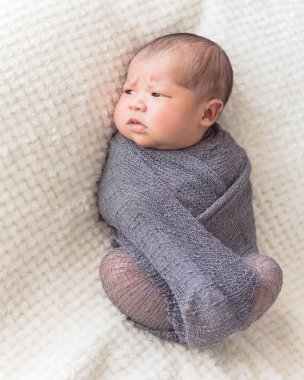 Mor örme tiftik şal giysili Asya bebek çocuk. 6 gün eski bebek yatakta rahat battaniye arka plan ile yatıyordu güzel portresi