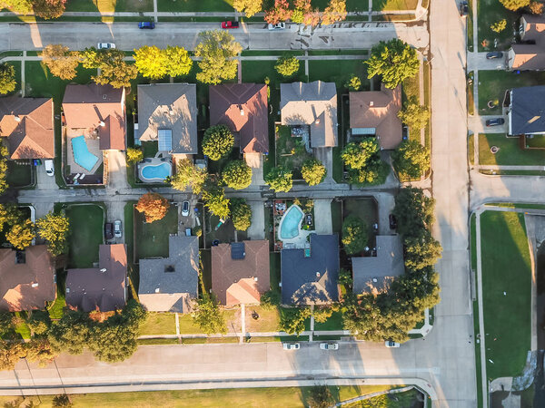 Panorama aerial vertical view residential houses with swimming pool in Carrollton, Texas, USA during fall sunset. Top view row of single-family homes with garden, driveway and attached garage