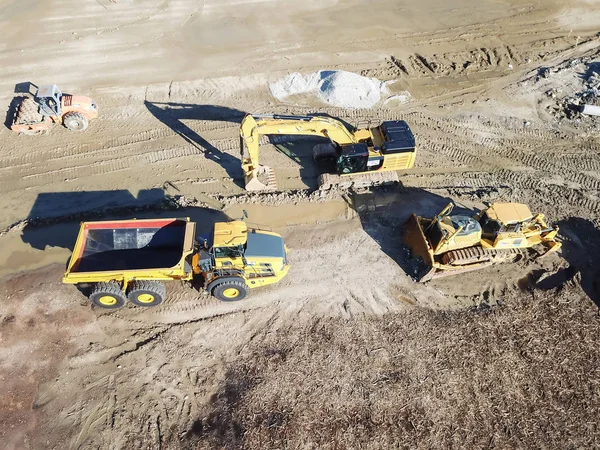 Aerial view machinery and heavy-duty equipments at large construction site in Carrollton, Texas, USA. Top of excavator, bulldozer, dump truck, digger