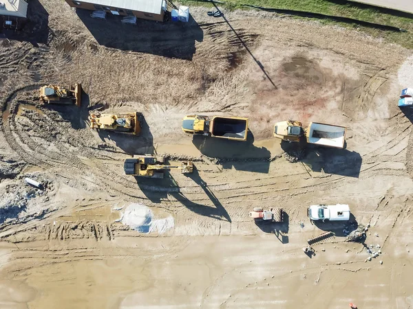 Top view machinery and heavy-duty equipments at large construction site in Carrollton, Texas, USA. Top of excavator, bulldozer, dump truck, digger and portable toilets