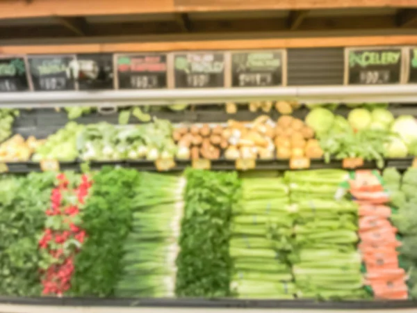 Blurred abstract wide selection of fresh vegetable on cooler display at grocery store. Defocused background raw organic produces at supermarket shelves