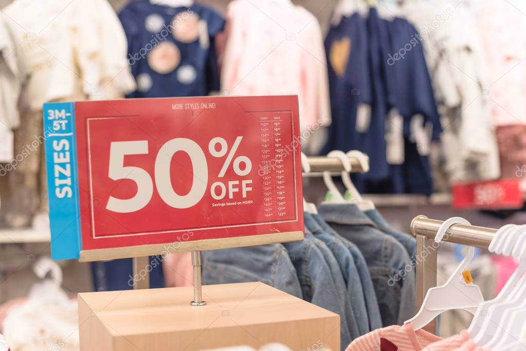 50 percent off sale sign over clothes at baby clothing store wit