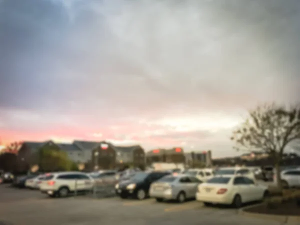 ぼやけて行劇的な夕焼けの雲の下でホテルの近くの卸売店の動き忙しい駐車場 — ストック写真