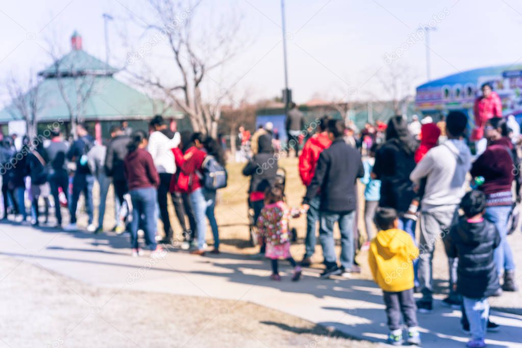 Blurry background multicultural people queue outdoor at festival event in USA