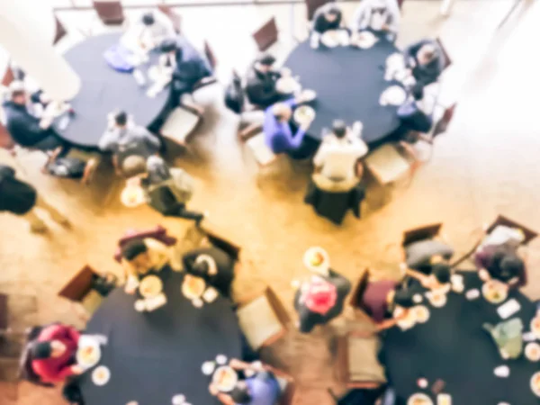 Blurry background crowded people at round banquet table in business event, top view