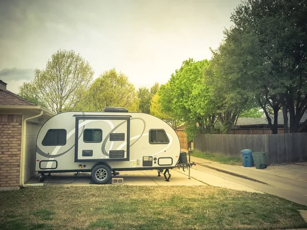 RV trailer parked at backyard of single family house, side view