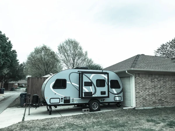 RV trailer parked at backyard of single family house, side view