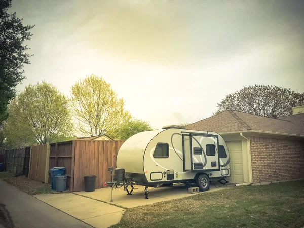 RV trailer parked at backyard of single family house, side view