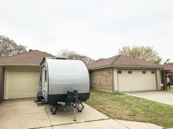 RV trailer parked at backyard of single family house, rear view