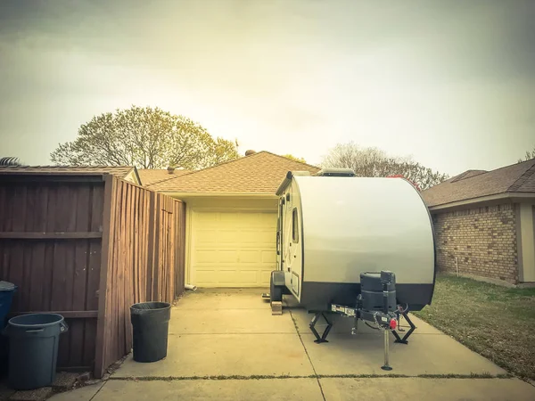 RV trailer parked at backyard of single family house, rear view