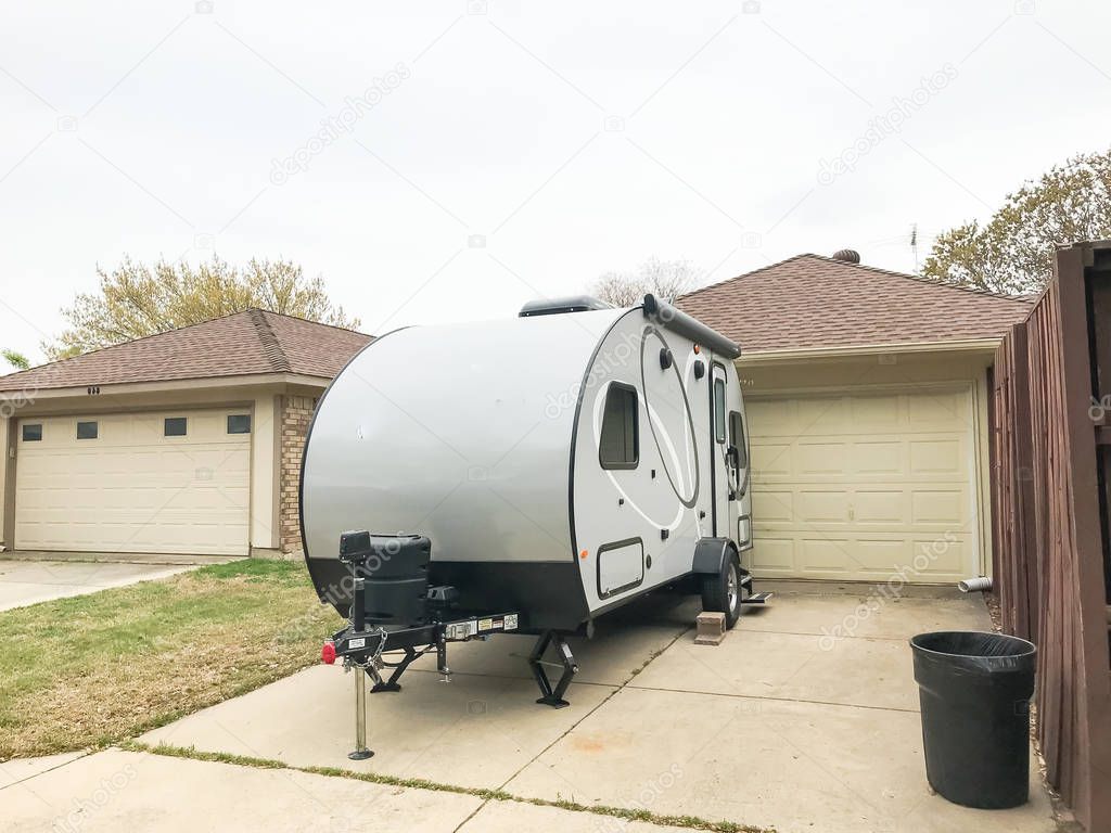 RV trailer parked at backyard of single family house, rear view