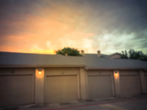 Filtrerad bild suddig bakgrund lägenhet komplex fristående garage täckt parkeringsplatser vid solnedgången — Stockfoto