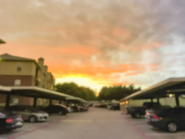 Suddig bakgrund typiskt lägenhetskomplex med fristående garage och täckta parkeringsplatser vid solnedgången — Stockfoto