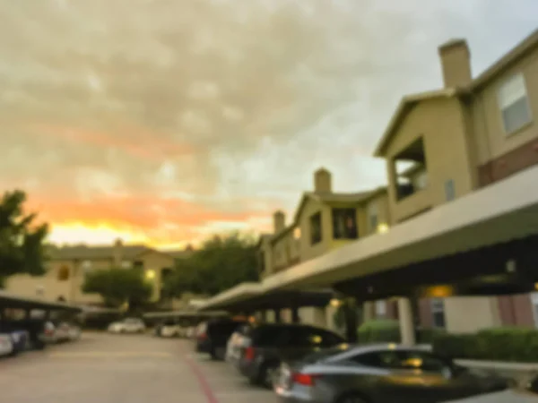 Blurry background typical apartment complex with detached garage and covered parking lots at sunset