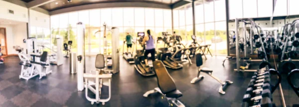Panoramic blurry background open fitness center with people workout at new home community