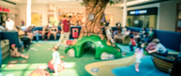 Panoramic view blurry background diverse kids playing at indoor soft playground inside shopping mall — Stock Photo, Image