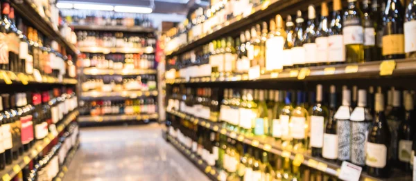 Panoramic view blurry background variety of wine bottles with price tags at liquor store