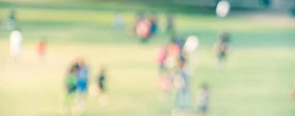 Vista panoramica sfondo sfocato bambini che corrono sul prato erboso al parco in America — Foto Stock
