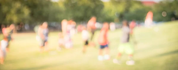 Panoramablick verschwommener hintergrund kinder laufen auf rasen im park in america — Stockfoto