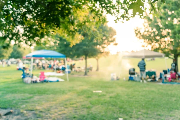 Rozmyte tło ludzie cieszyć się grill i Camping w miejscowym parku o zachodzie słońca — Zdjęcie stockowe