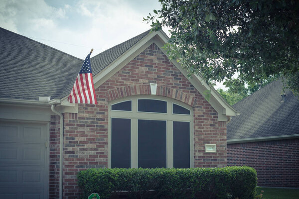 Filtered image facade of American home proudly displaying flag