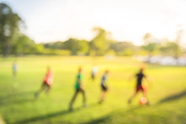 Blurry background Latin America boys playing soccer at park during sunset