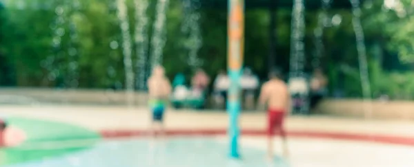 Panorama ver fondo borroso padres y niños disfrutan de la almohadilla de salpicadura de agua en la hora de verano —  Fotos de Stock