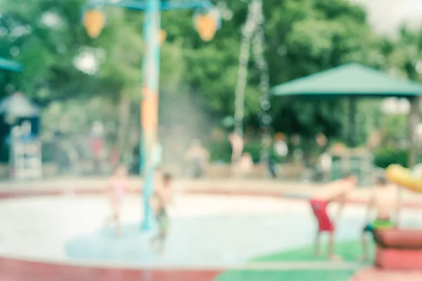 Розмитий фон батьки і діти насолоджуються водяними бризками в літній час — стокове фото