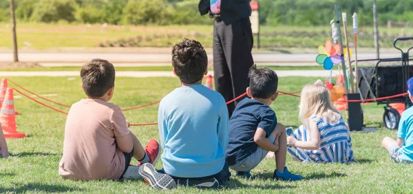 Panoramique gros plan arrière vue multiculturelle enfants sur herbe prairie de jeu en plein air — Photo