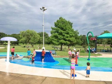Çok kültürlü çocuklar ve ebeveyn yaz fırtınalı hava altında splash parkta oynuyor