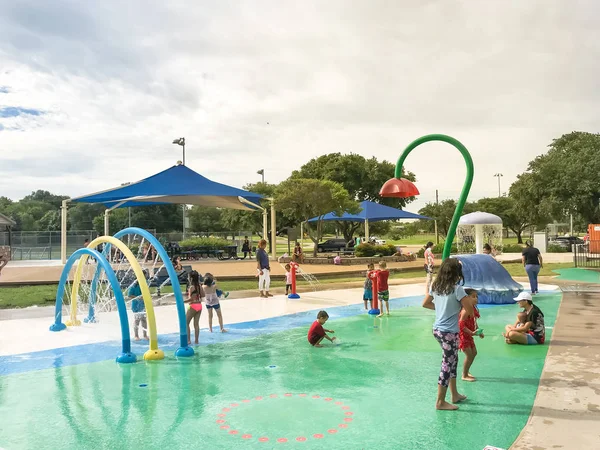 Multikulti-Kinder und Eltern spielen bei sommerlichem Unwetter im Planschpark — Stockfoto