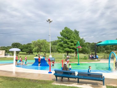 Çok kültürlü çocuklar ve ebeveyn yaz fırtınalı hava altında splash parkta oynuyor