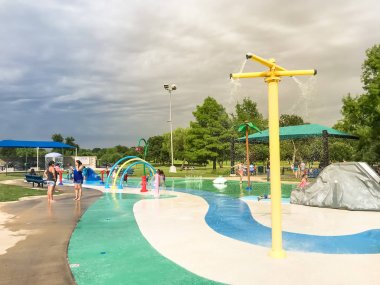 Çok kültürlü çocuklar ve ebeveyn yaz fırtınalı hava altında splash parkta oynuyor