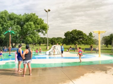 Çok kültürlü çocuklar ve ebeveyn yaz fırtınalı hava altında splash parkta oynuyor